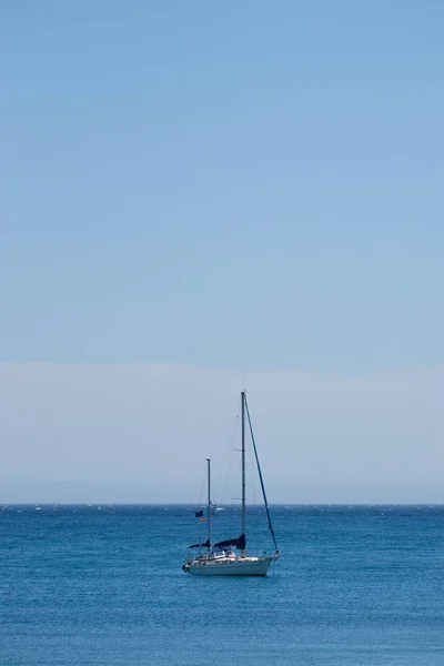 背景に澄んだ青い空を背景に 海を航海する小さなボートの垂直ショット — ストック写真