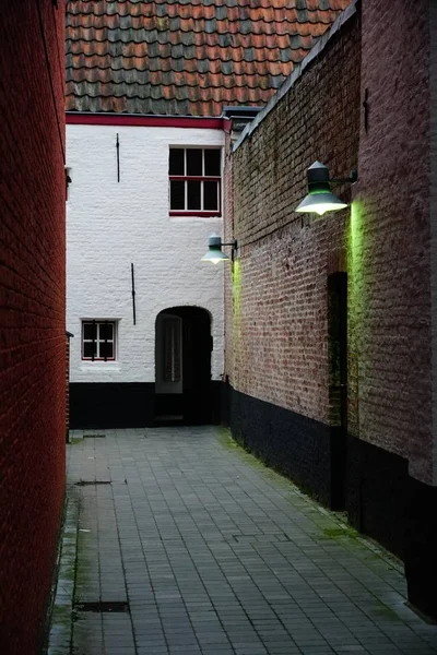 Tiro vertical de uma ruela dentro de edifícios com luzes na parede — Fotografia de Stock