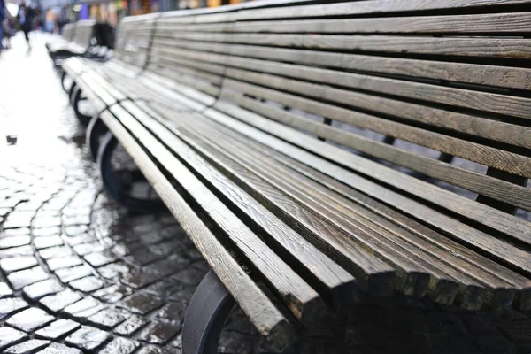 Wooden bench on the sidewalk with a blurred background — Stock Photo, Image