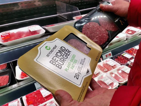 スペインのマラガ 2020年2月8日 白人男性が間に躊躇野菜で作られた肉バーガーとスーパーマーケットで通常の肉を超えて 背景に普通の肉の棚 — ストック写真