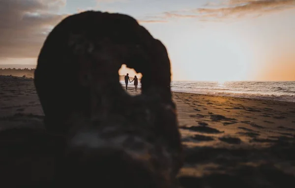 Masculino e uma fêmea segurando as mãos uns dos outros capturados a partir do pequeno buraco na rocha — Fotografia de Stock