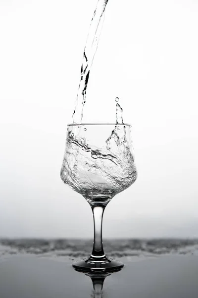 Eine Vertikale Graustufenaufnahme Eines Wasserglases Auf Verschwommenem Hintergrund — Stockfoto