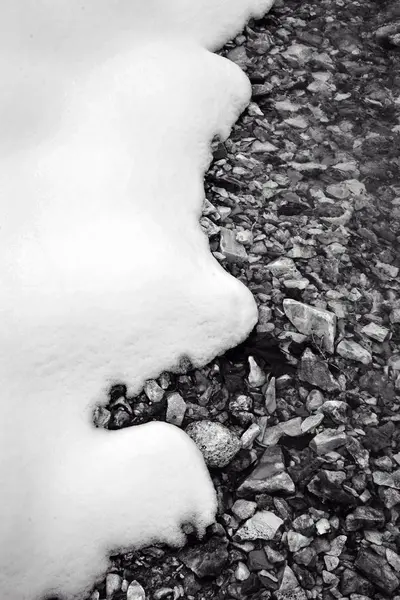 Pionowa Skala Szarości Ziemi Pokrytej Małymi Skałami Śniegiem Zimie — Zdjęcie stockowe