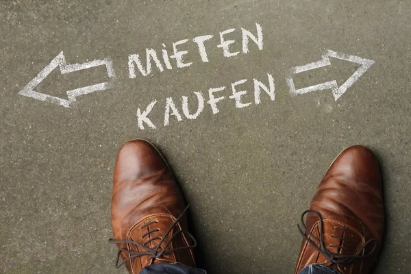 Homme regardant vers le bas les mots "MIETEN" et "KAUFEN" (location et achat en allemand) — Photo