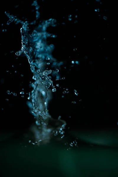 黒い背景に青い水のスプラッシュの垂直クローズアップショット — ストック写真