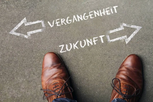 Avec des chaussures en cuir brun entre "VERGANGENHEIT" et "ZUKUNFT" (passé et futur en allemand) — Photo