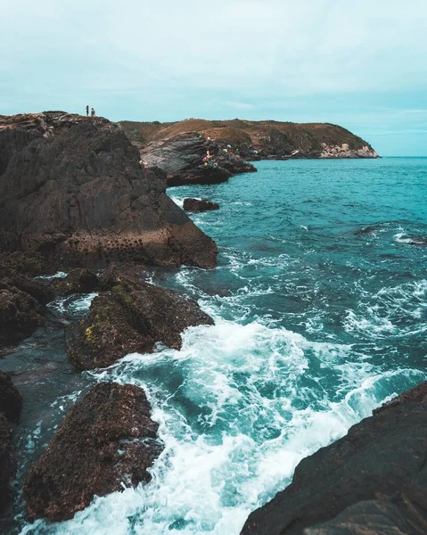 一道高角度的海浪拍打在岩石上 背景是多云的天空 — 图库照片