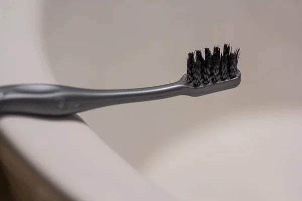 Μια Μαύρη Οδοντόβουρτσα Τοποθετημένη Ένα Μπάνιο Πίσω Από Ένα Λευκό — Φωτογραφία Αρχείου