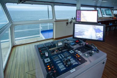 IJMUIDEN, NETHERLANDS - Sep 01, 2017: The center console in the wheelhouse of a ferry. There are a lot of buttons and computer screens designed for steering the ship clipart