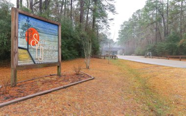 LAKE CHARLES, UNITED STATES - Feb 09, 2018: Lake Charles, Louisiana - February 2018: A wooden sign greets visitors on the entrance road to Sam Houston Jones State Park. clipart