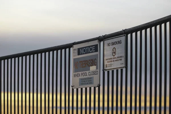 Znaki Ostrzegawcze Pobliżu Plaży Metalowym Ogrodzeniu Podczas Zachodu Słońca — Zdjęcie stockowe