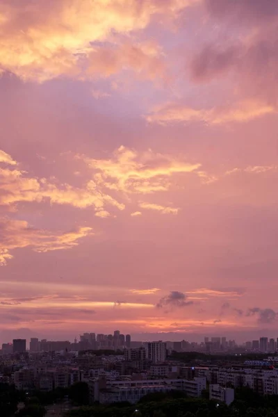 日没時にオレンジ色のピンク色の空の下で都市の建物の垂直空中ショット — ストック写真