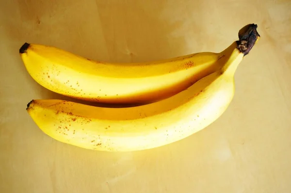 Ένα Κοντινό Πλάνο Δύο Μπανάνες Ένα Ξύλινο Τραπέζι — Φωτογραφία Αρχείου