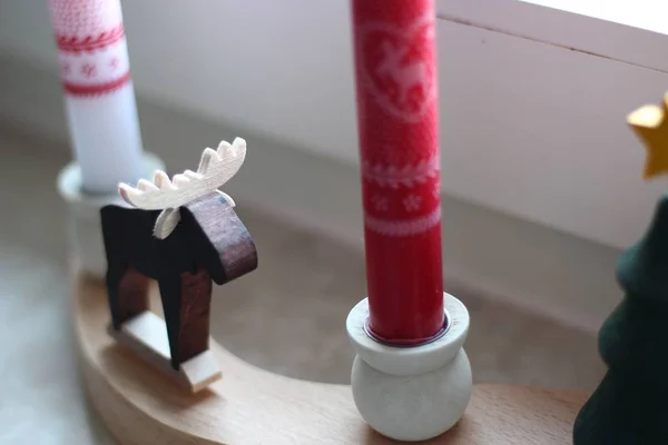 在木制表面的圣诞蜡烛之间的一只装饰麋鹿的特写镜头 — 图库照片