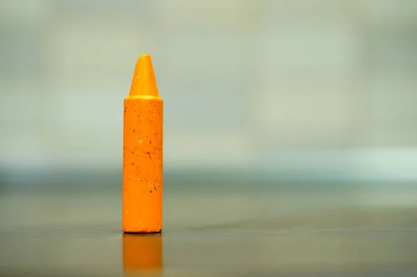 Tiro Close Crayon Laranja Uma Superfície Reflexiva — Fotografia de Stock
