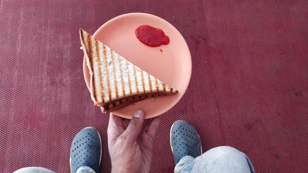 サンドイッチとケチャップで皿を持っている人の高角度ショット — ストック写真