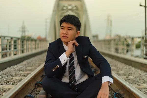 Mladý Asijský Podnikatel Který Sedí Uprostřed Železnice Dívá Jinam Bradou — Stock fotografie