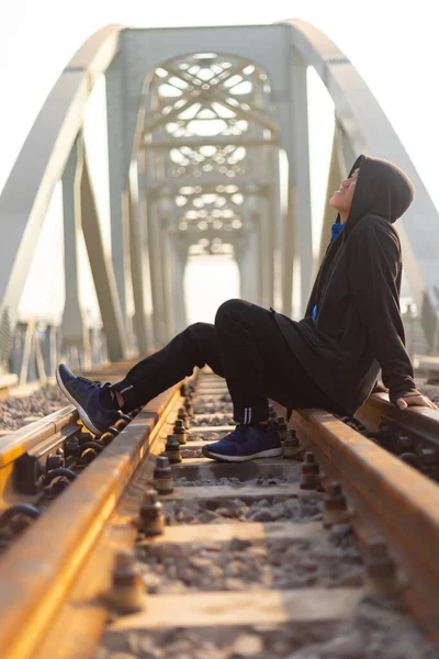 Giovane Con Una Giacca Incappucciata Seduto Nel Mezzo Una Ferrovia — Foto Stock