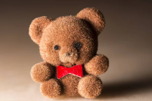 Ein Brauner Niedlicher Teddybär Mit Roter Schleife Auf Braunem Hintergrund — Stockfoto