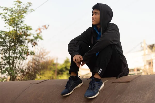 Ein Junger Mann Lässiger Kleidung Sitzt Auf Einem Betonrohr Und — Stockfoto