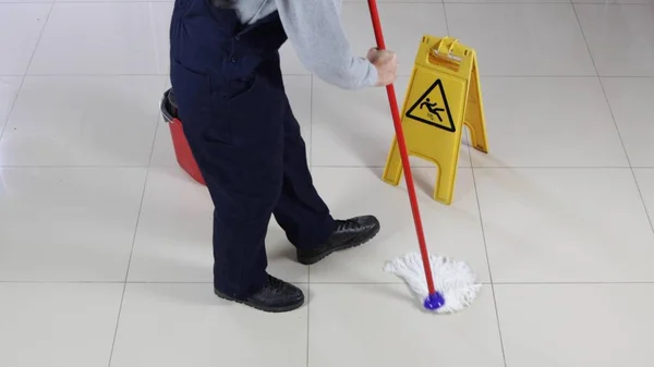 床を掃除する男と慎重にサインぬれた床 — ストック写真
