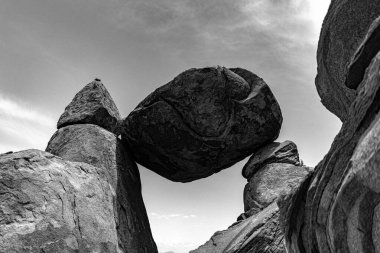 A low angle greyscale shot of a large boulder balanced on rocks in Grapevine Hills, Texas USA clipart