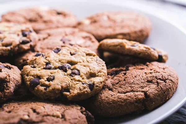 A closeup shot of a lot of chocolate chip cookies in a white plate