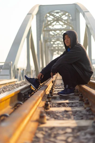 Giovane Asiatico Con Giacca Incappucciata Seduto Nel Mezzo Una Ferrovia — Foto Stock