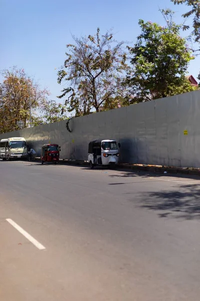 カンボジアプノンペンの道路脇に停まっている車や人力車 — ストック写真