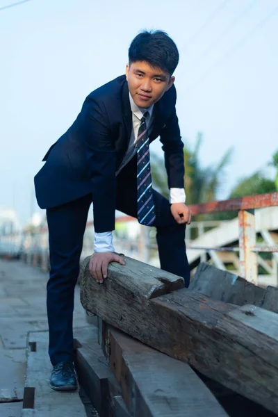 Ein Junger Asiatischer Mann Anzug Kauerte Auf Einem Holzstapel — Stockfoto