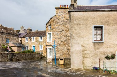 Beautiful buildings in Stromness, Orkney in Scotland with a cloudy gray sky in the background clipart