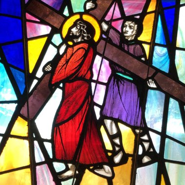 OCEAN SPRINGS, UNITED STATES - May 09, 2019: Stained glass image of Simon of Cyrene helping Jesus carry His Cross. Taken at St. Alphonse Church. clipart