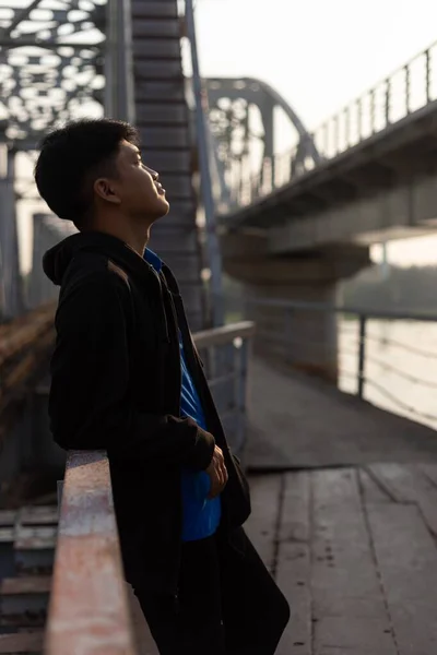 Giovane Uomo Asiatico Appoggiato Una Ringhiera Ponte Guardando Alto — Foto Stock
