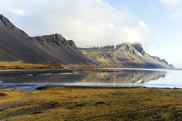 冰岛一个风景秀丽的湖畔有着独特斜坡的雄伟山脉的全景照片 — 图库照片