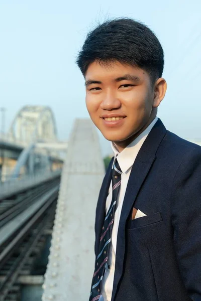 Köprüde Dikilen Gülümseyen Takım Elbiseli Asyalı Genç Bir Adamın Yakın — Stok fotoğraf