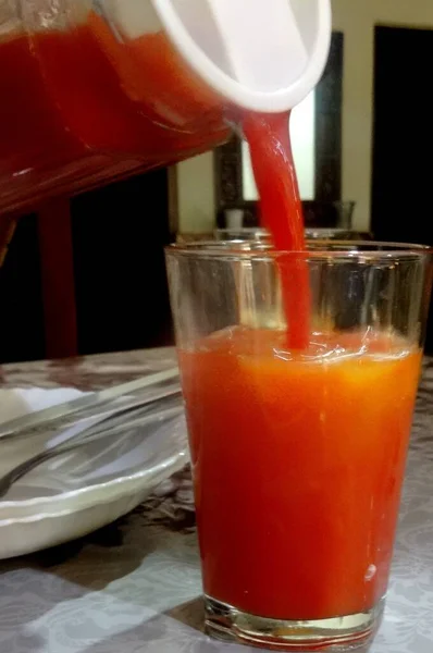 ガラスに注ぎ込まれた赤いジュースの垂直閉鎖ショット — ストック写真