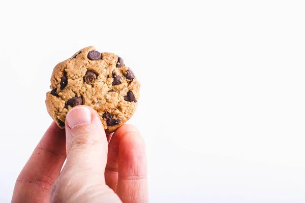 白い背景に隔離されたチョコレートチップクッキーを持っている人のクローズアップショット — ストック写真