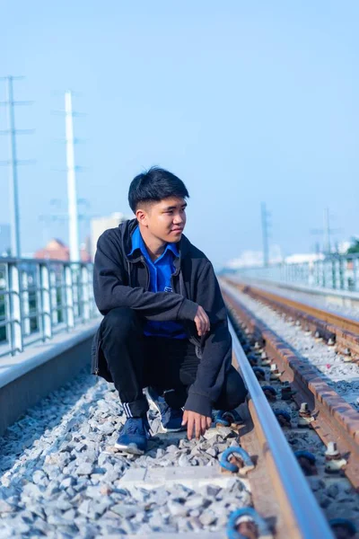 Ein Junger Asiatischer Mann Lässiger Kleidung Kauerte Auf Einer Eisenbahn — Stockfoto