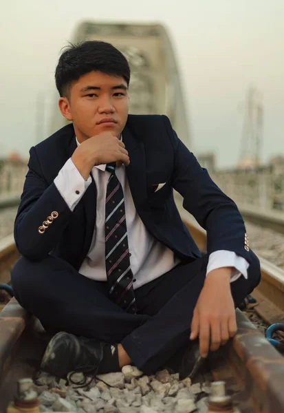 Detailní Záběr Mladého Asiata Obleku Sedícího Uprostřed Železnice Bradou Ruce — Stock fotografie