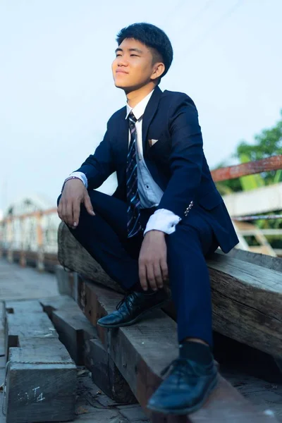 Joven Asiático Con Traje Sentado Montón Troncos Mirando Hacia Otro —  Fotos de Stock