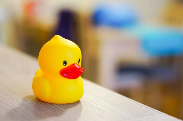 A closeup shot of a yellow rubber duck on the table with a blurred background