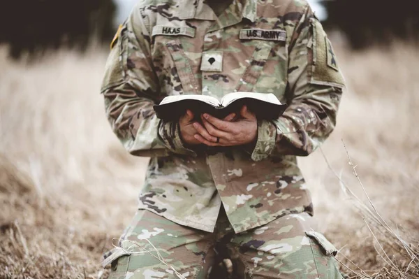 Shallow Focus Shot Young Soldier Kneeling While Holding Bible Field — Stock Photo, Image