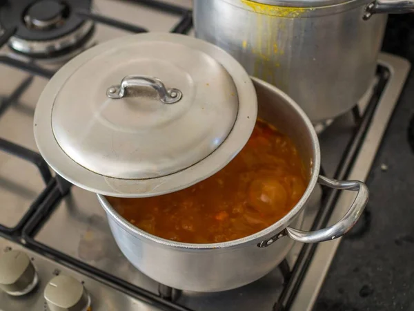 A saucepan with a soup boiling and a metal lid