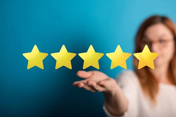 An evaluation and rating concept. A woman holding five stars against a blue background