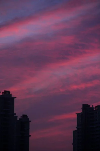 カラフルな夕日の空に対して都市の建物のシルエットの垂直ショット — ストック写真