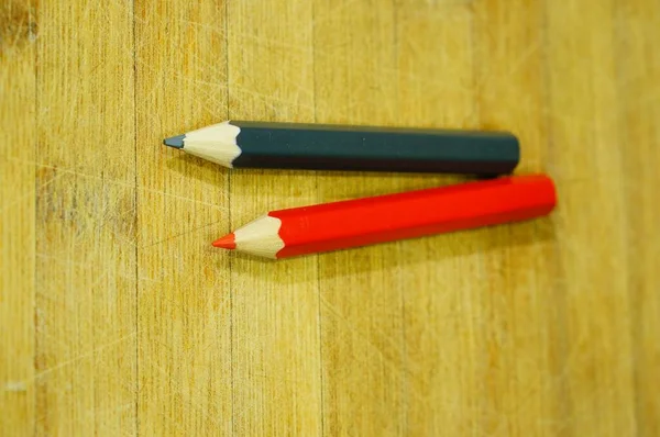 木製の表面に2本の赤と灰色の描画鉛筆の垂直クローズアップショット — ストック写真