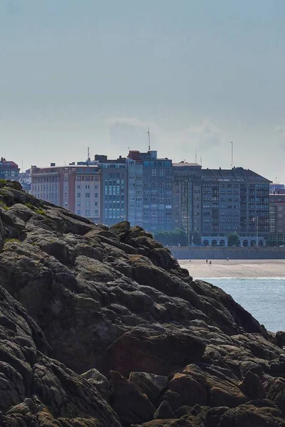 西班牙科鲁纳海域和背景建筑上的岩石垂直拍摄 — 图库照片