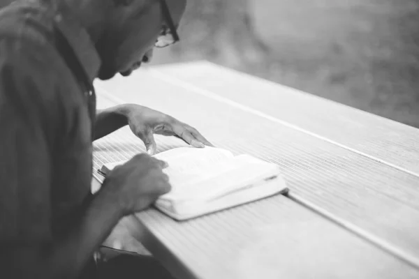 Szare Ujęcie Afroamerykanina Siedzącego Przy Stole Czytającego Biblię — Zdjęcie stockowe
