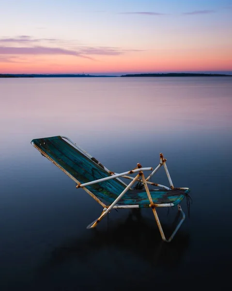 Pionowe Ujęcie Pojedynczego Zardzewiałego Krzesła Jeziorze Podczas Zachodu Słońca Szwecji — Zdjęcie stockowe