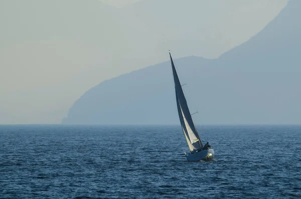 Ett Litet Segelfartyg Havet Omgivet Berg Täckt Dimma Dagen — Stockfoto